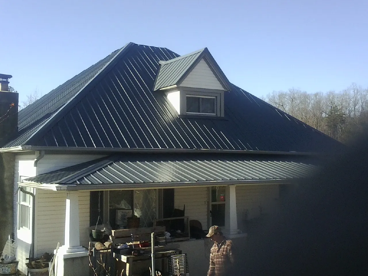 Dark blue standing seam metal roof with a dormer above a front porch in Rockwood